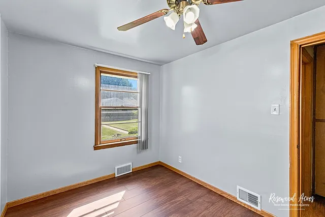 a view of an empty room with window and wooden floor
