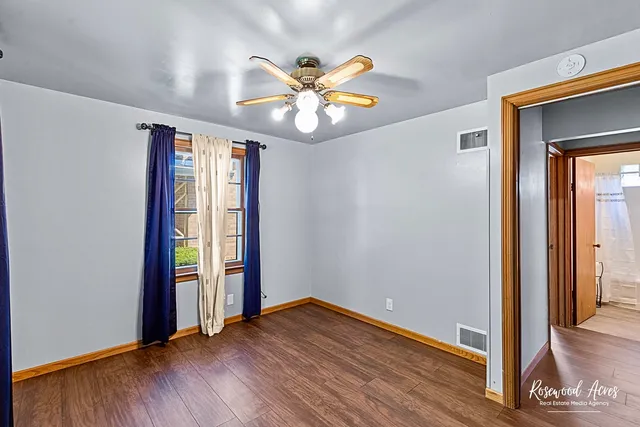a view of an empty room with window and wooden floor