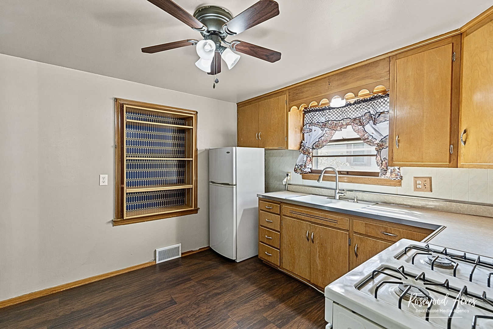 1054 South 7th Avenue Kankakee, IL 60901 - Photo 17 of 30 a kitchen with stainless steel appliances a stove a sink and white cabinets with wooden floor next to windows