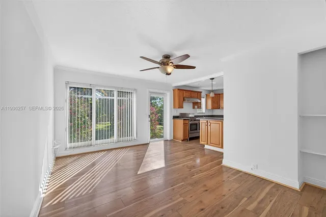 a view of an empty room with a window and wooden floor