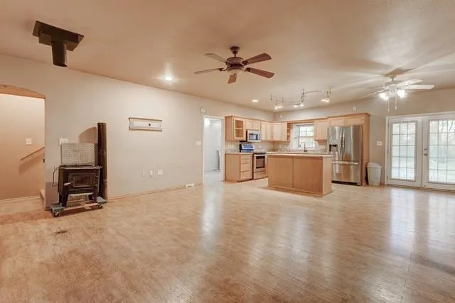 a view of an empty room with a window and kitchen view
