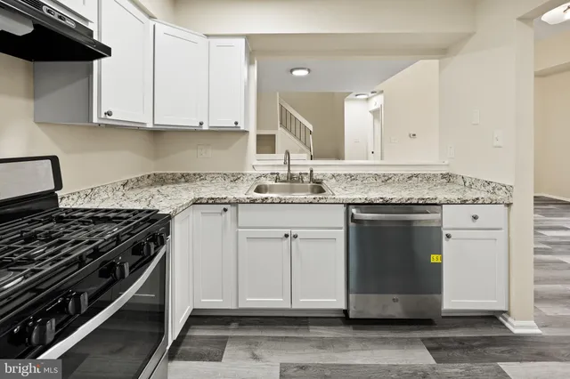 a kitchen with granite countertop stainless steel appliances a sink and cabinets