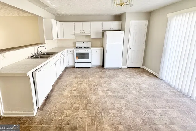 a kitchen with white cabinets and white appliances
