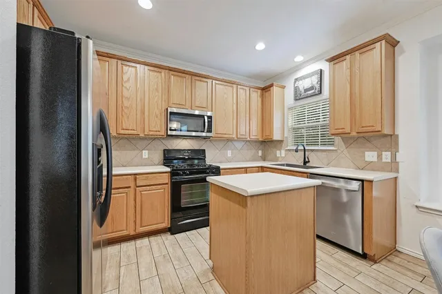 a kitchen with stainless steel appliances granite countertop a stove a sink dishwasher a refrigerator and a microwave