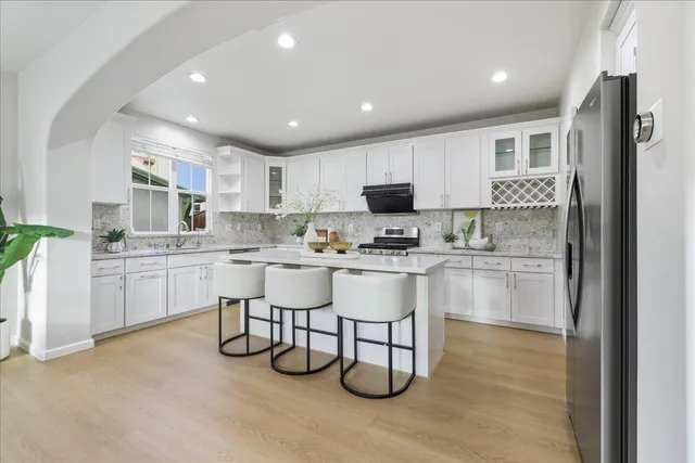a living room with stainless steel appliances kitchen island granite countertop furniture and a chandelier