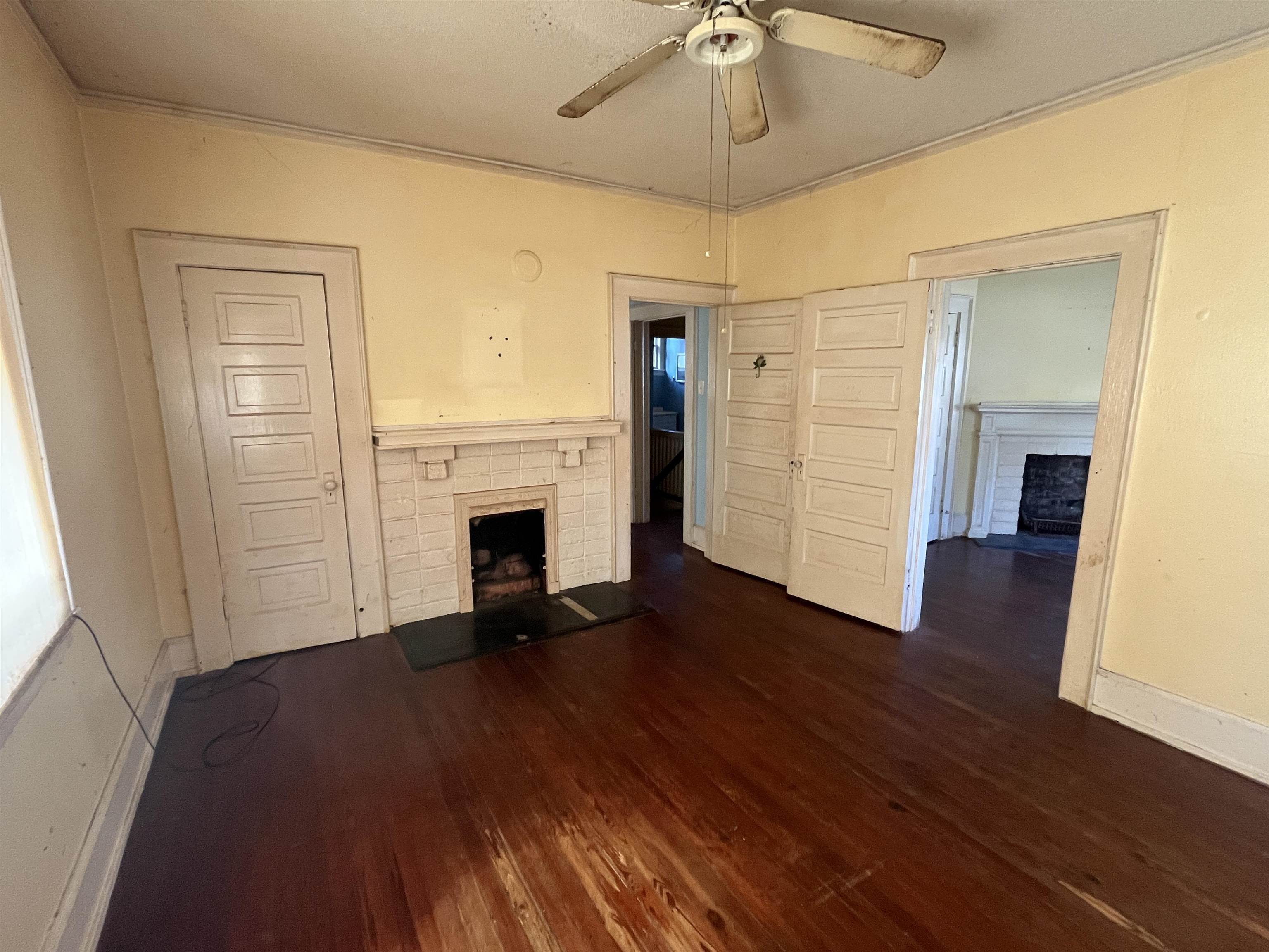 211 4th Street Mobile, AL 36611 - Photo 27 of 34 Unfurnished living room with a fireplace with raised hearth, dark wood-type flooring, a ceiling fan, and ornamental molding