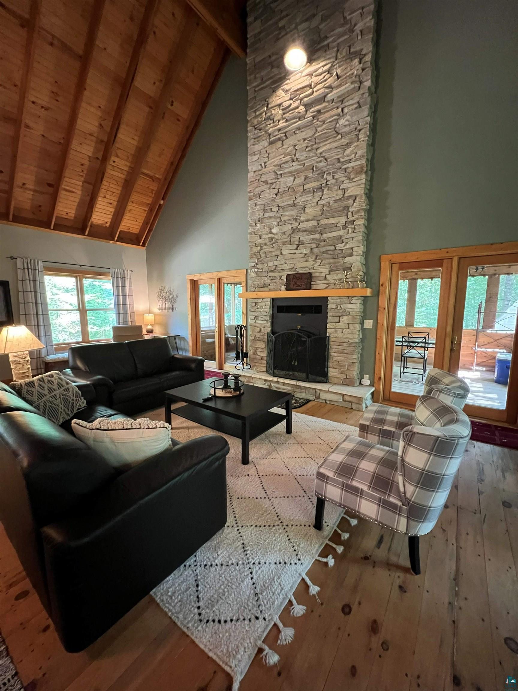 87645 Bjorn Road Bayfield, WI 54814 - Photo 7 of 13 Living area with hardwood / wood-style flooring, a stone fireplace, a high wooden beamed ceiling, and french doors