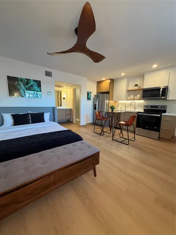 a kitchen with stainless steel appliances kitchen island granite countertop a refrigerator a stove a sink dishwasher and a dining table with wooden floor