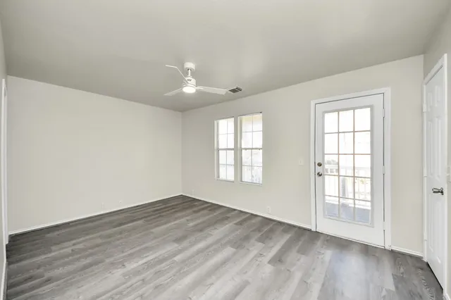 an empty room with wooden floor and windows