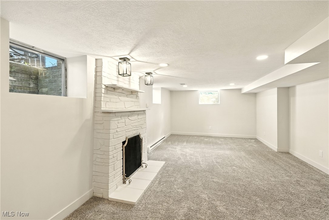 2844 Kent Road Stow, OH 44224 - Photo 33 of 47 Below grade area with a fireplace with flush hearth, light colored carpet, baseboard heating, and a textured ceiling