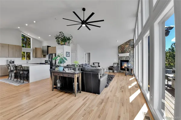 a living room with stainless steel appliances kitchen island granite countertop furniture wooden floor and a large window