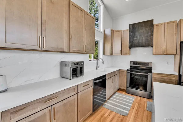 a kitchen with stainless steel appliances granite countertop a stove a sink and a white cabinets