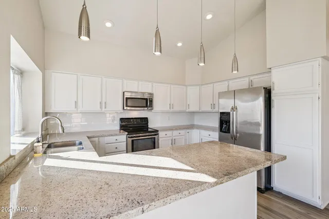 a kitchen with stainless steel appliances granite countertop a sink a stove a refrigerator a center island with wooden floor and cabinets