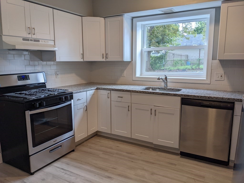 511 Buffinton Street, Unit A Fall River, MA 02721 - Photo 2 of 15 a kitchen with granite countertop white cabinets appliances a sink and a window
