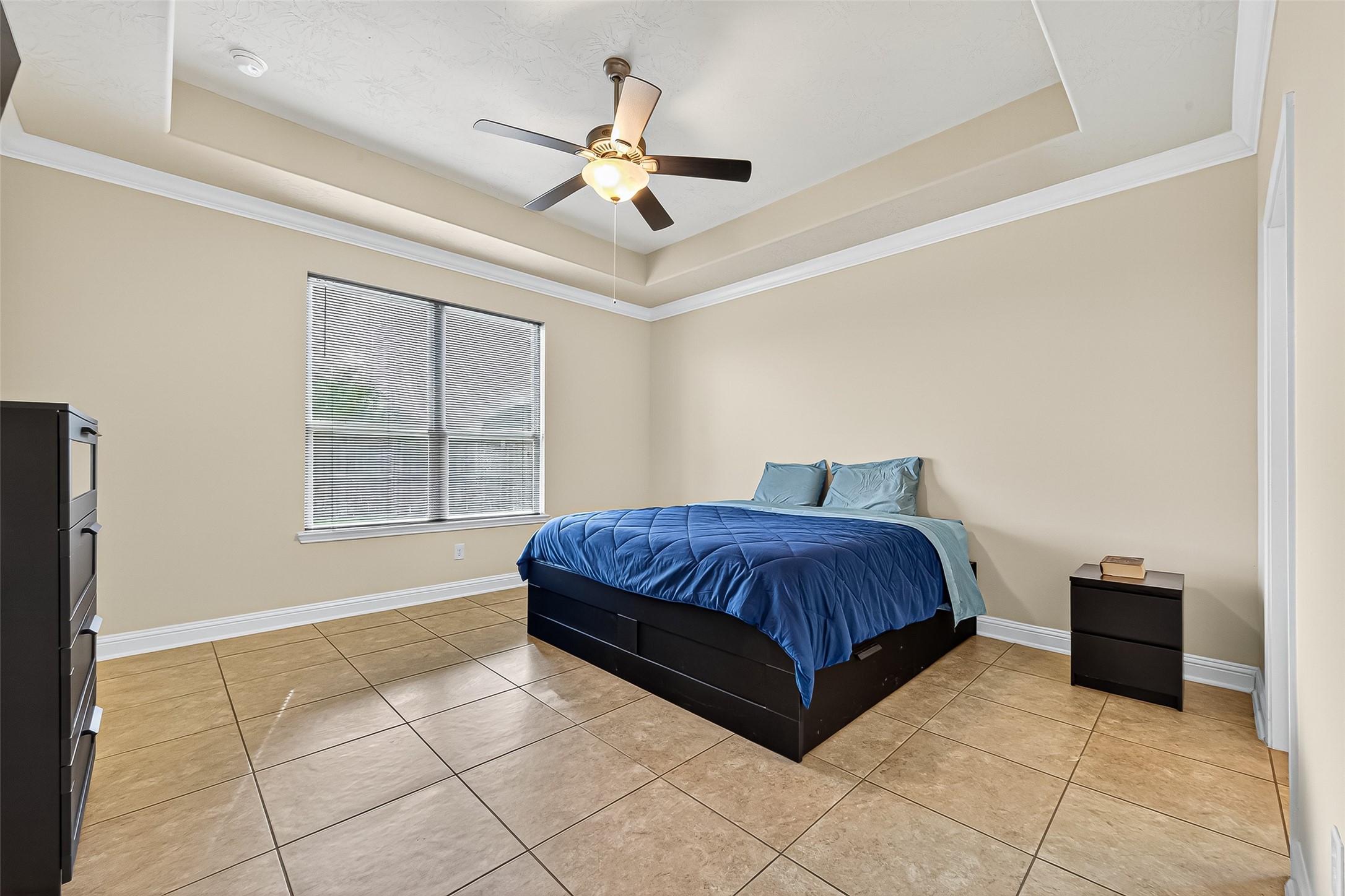8107 Lockridge Terrace Lane Cypress, TX 77433 - Photo 28 of 50 This spacious primary bedroom exudes comfort and tranquility with its elegant tray ceiling, neutral tones, and abundant natural light. Ceramic tile flooring adds durability and easy maintenance, while large windows offer serene views and a soothing atmosphere—your perfect retreat at the end of each day.
