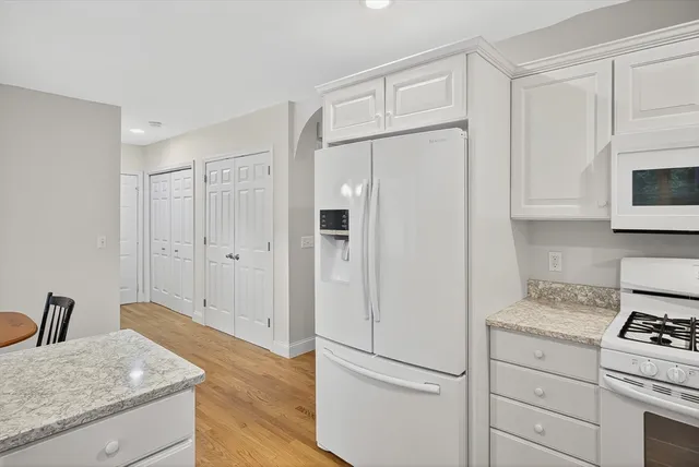 a kitchen with granite countertop white cabinets and white appliances