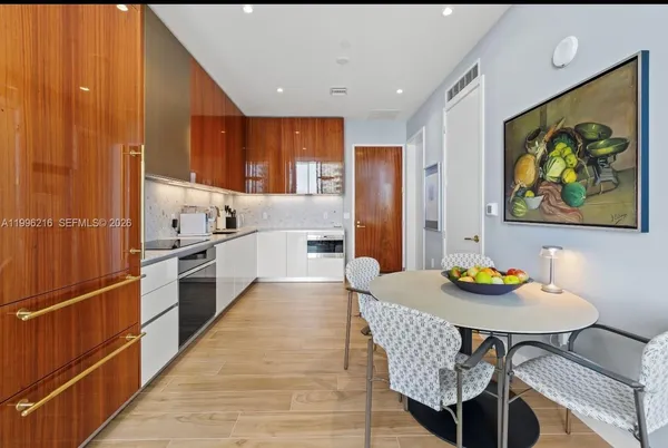a kitchen with stainless steel appliances granite countertop a dining table chairs and a refrigerator