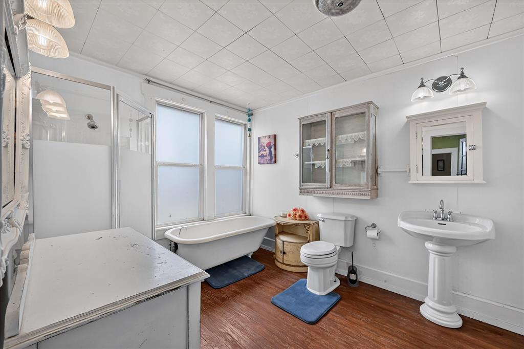 304 East Main Street Itasca, TX 76055 - Photo 20 of 38 Pedestal sink with chrome fixtures, a clawfoot tub, and a separate shower enclosure