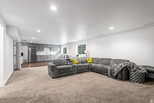 313 Old Maple Road South Weber, UT 84405 - Photo 21 of 35 Open-concept room featuring recessed lighting, plush carpeting, a kitchen area with gray cabinetry and stainless steel appliances, and wood-finish flooring