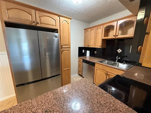 a kitchen with stainless steel appliances granite countertop a refrigerator a stove and a sink with wooden floors