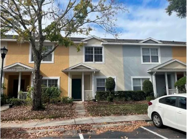 a view of a white house with a large tree next to a yard