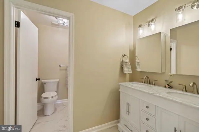 a bathroom with a granite countertop sink a toilet and a mirror