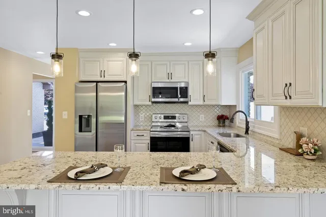a kitchen with granite countertop kitchen island stainless steel appliances sink refrigerator and stove