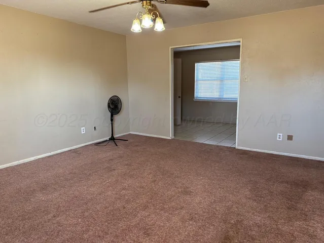 a view of an empty room with a chandelier fan