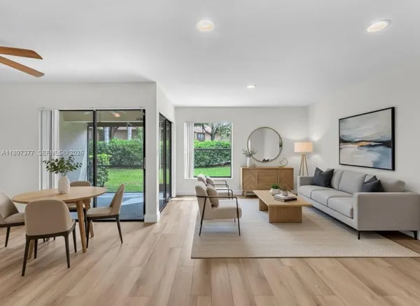 a living room with furniture large windows and wooden floor