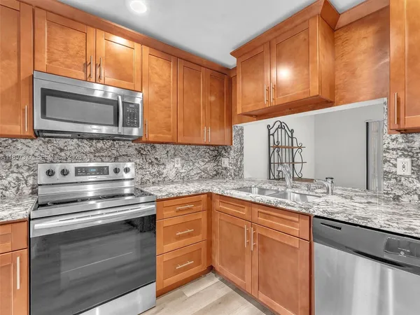a kitchen with stainless steel appliances granite countertop wooden cabinets and a stove top oven