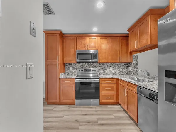 a kitchen with stainless steel appliances granite countertop a stove a sink and a refrigerator
