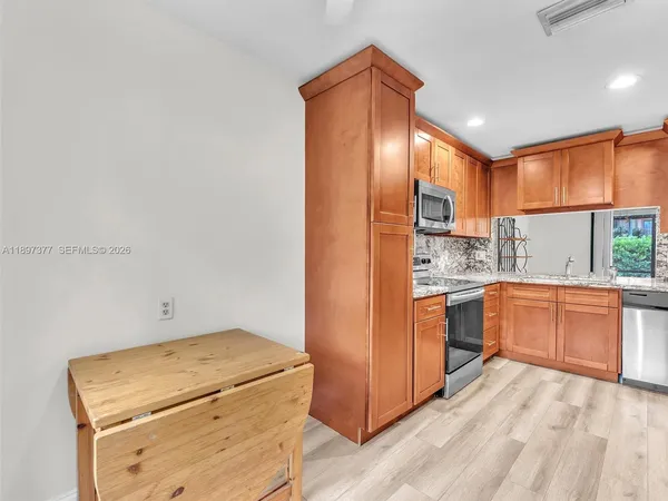 a kitchen with a refrigerator a stove top oven cabinetry a sink and a window