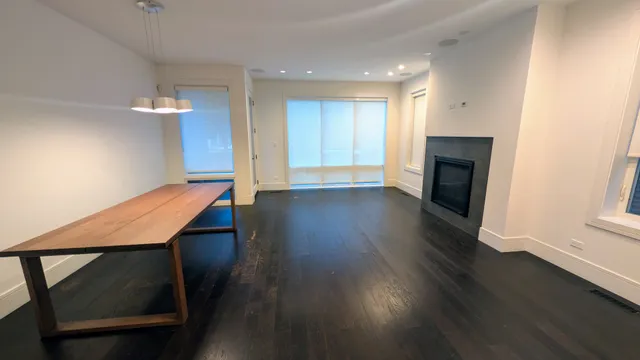 an empty room with wooden floor fireplace and windows