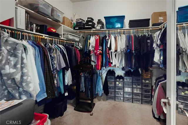 a view of walk in closet with clothes and shoes