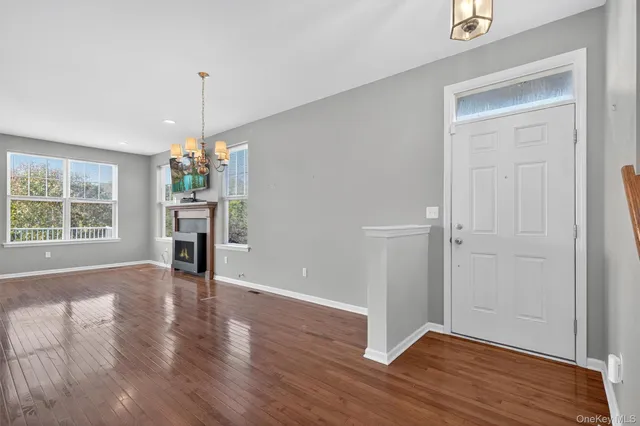 an empty room with wooden floor chandelier and windows