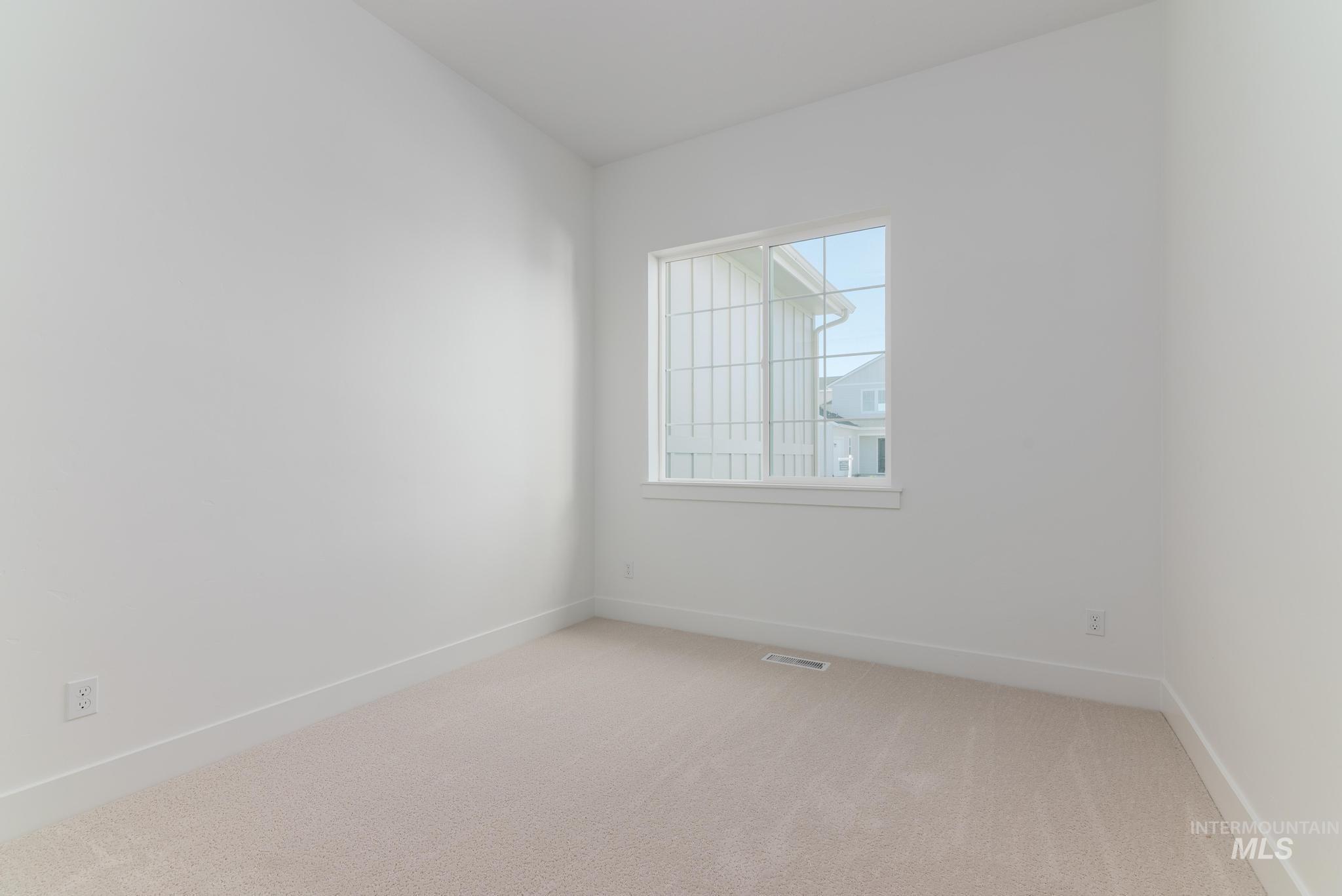 9074 West Moonglade Street Star, ID 83669 - Photo 25 of 40 Bright interior space featuring a grid-pattern window, light beige carpet, white walls, and white baseboards
