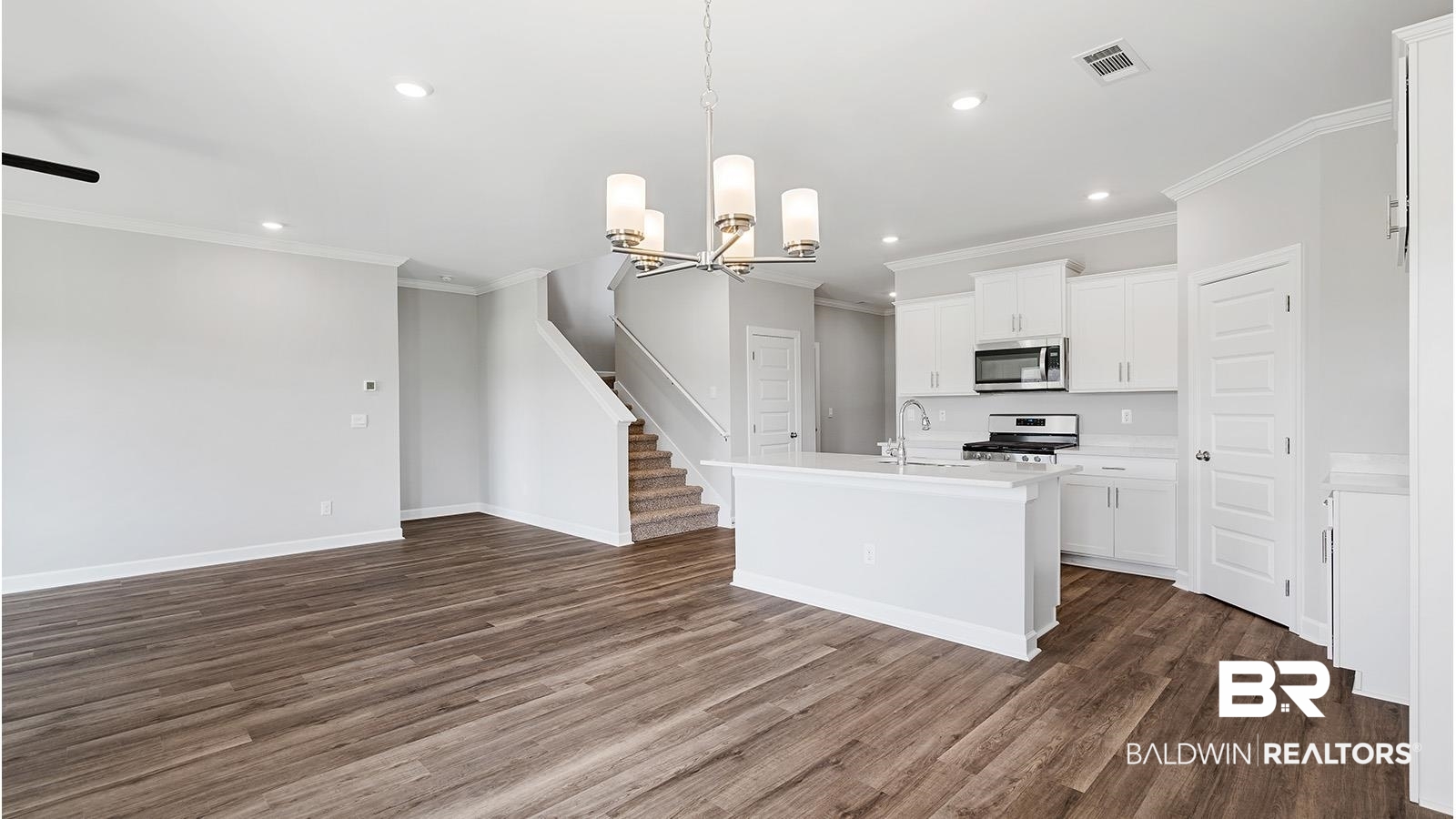 30567 Asheville Road Daphne, AL 36527 - Photo 29 of 29 Kitchen with hanging light fixtures, ornamental molding, open floor plan, a kitchen island with sink, and white cabinets