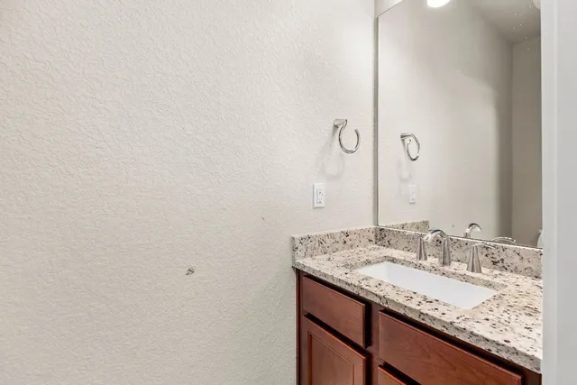 a bathroom with a granite countertop sink and a mirror