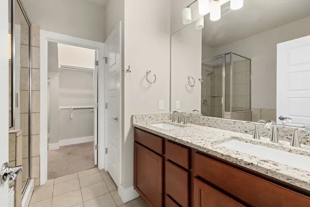 a bathroom with a granite countertop sink two mirror and a shower