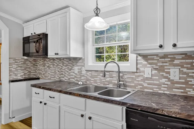 a kitchen with stainless steel appliances kitchen island granite countertop a refrigerator stove and white cabinets