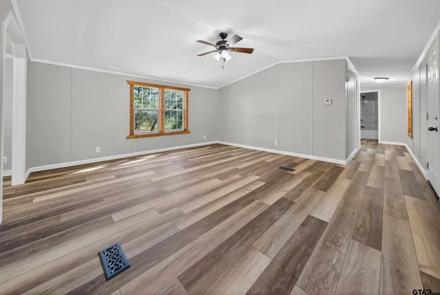 a view of empty room with wooden floor and fan
