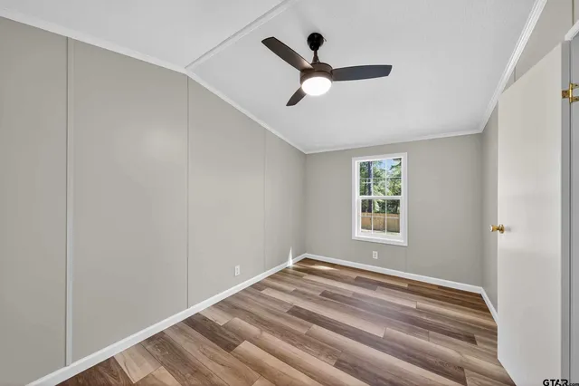 a view of empty room with wooden floor and fan
