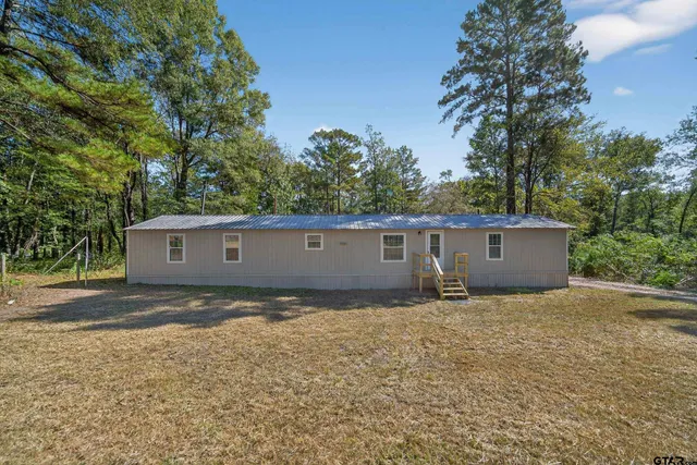 a view of a house with a backyard and trees