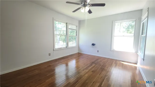 a view of an empty room with wooden floor and a window