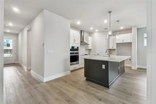 a large kitchen with stainless steel appliances granite countertop a large counter top and wooden floors