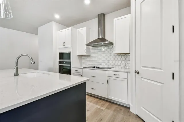 a kitchen with a sink a center island a wooden floor and a large window