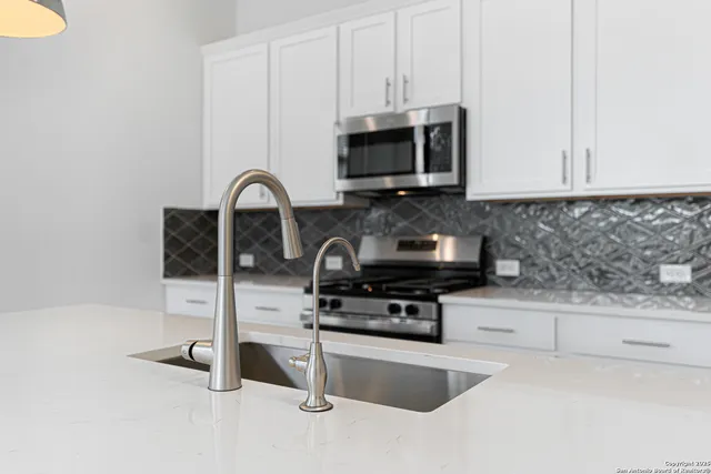 a kitchen with granite countertop white cabinets and stainless steel appliances