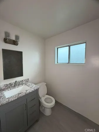 a bathroom with a granite countertop toilet a sink and a mirror