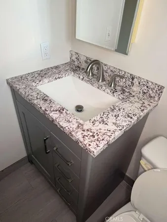 a bathroom with a granite countertop sink and a toilet