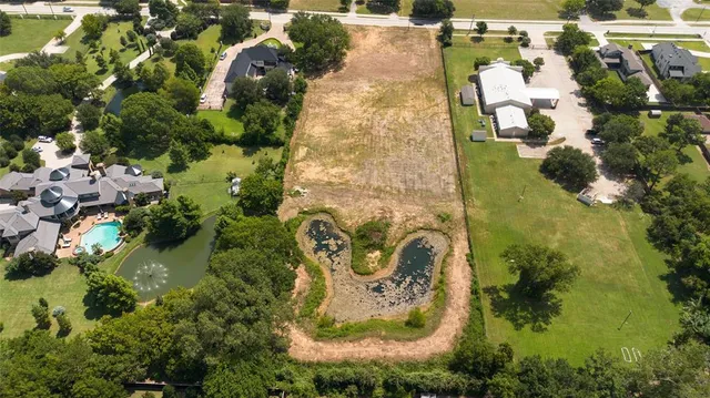 an aerial view of a house with swimming pool and large trees